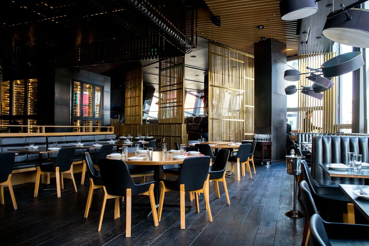 éxitoweb — interior de un restaurante moderno con mesas de madera y luz cálida, ejemplo del estilo de las webs entregadas